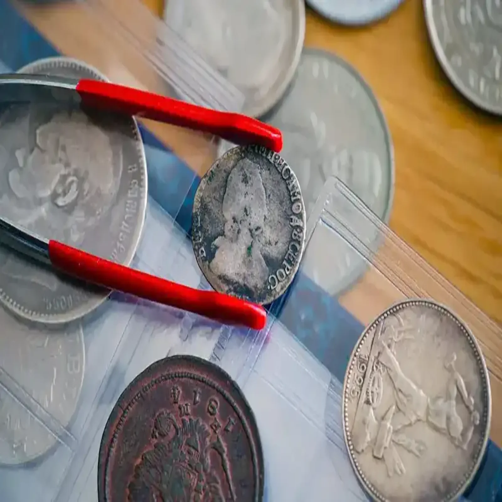 Gloved hands holding a coin and banknote near a display frame